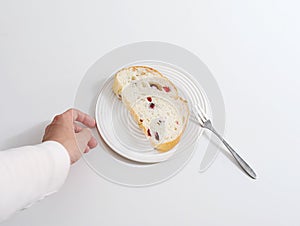 Hand reaching for a piece of bread on a plate