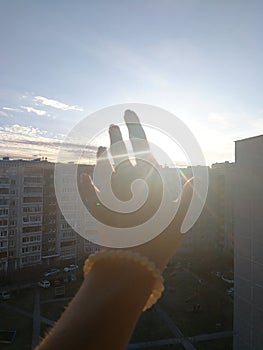 The hand reaching towards the sun in the sky at the time of the sunset