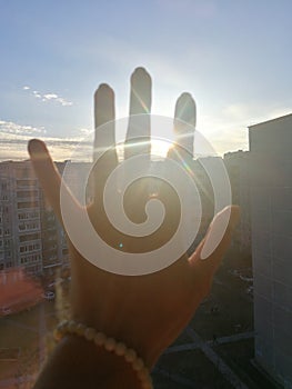 The hand reaching towards the sun in the sky at the time of the sunset