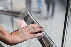 Hand reading Braille inscriptions for the blind on public amenity railing photo