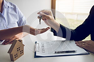 Hand of real estate agent passes the key to new homeowners in office with buyer house concept