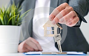 Hand of real estate agent or property realtor giving house key to buyer after singing contract