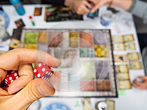 Hand with red dice on the game board with a four