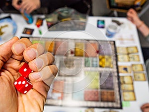 Hand with red dice on the game board with a one and a three