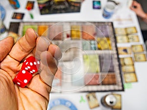 Hand with red dice on the game board with a three and two