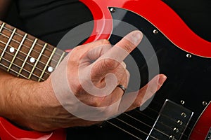 Hand with red guitar and devil horns on black