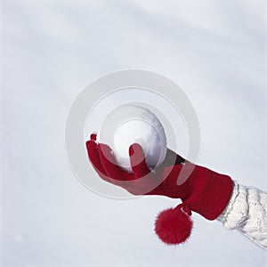 Hand with red knit glove holding snowball