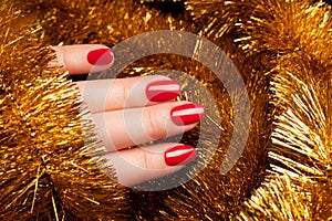 Hand with red nails with golden tinsel