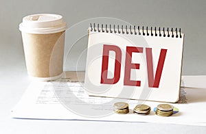 Hand with red pen. Cofee cup. Stick. Keyboard and white background. DEV sign in the notepad