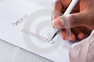 Hand with red pen marking a check box