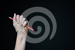 Hand with red pencil tied with rope