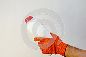A hand in a red protective glove holds a plastic container again