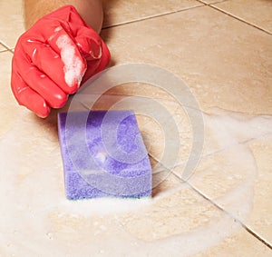 Hand in red rubber glove clean a house floor