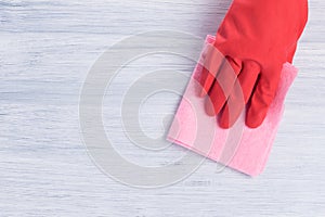 Hand in a red rubber glove wipes the table surface with a rag