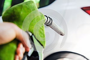 hand refilling a car with fuel at a gas station