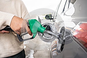 Hand refilling the car with fuel at the refuel station. Grey car at gas station being filled with fuel at New Zealand. Handle fuel