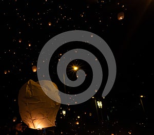 hand releasing a Chinese lantern into the air at night thousands of flying lanterns. Christmas
