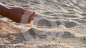 Hand releasing dropping sand flowing through fingers