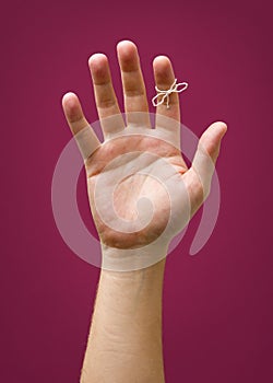 Hand with remider string isolated on red purple plum background photo