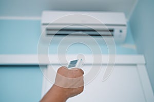 Hand with remote control directed on air conditioner