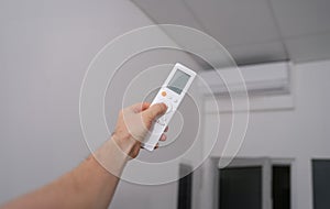 Hand with the remote control is directed to air conditioner