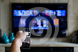 Hand with a remote control. Whats on tv, sliding through apps en movies on your television