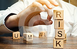 Hand removes blocks with the word Risk. The concept of reducing possible risks. Insurance, stability support. Financial pillow.