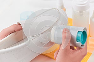 Hand removing dirt from a white leather loafer using a sponge detergent