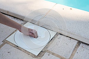 Hand removing the lid from a pool skimmer