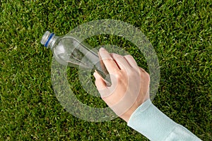 hand removing plastic bottle from grass