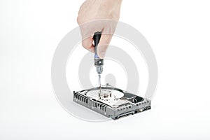 Hand repairman unscrews the cover of the engine of the open 3.5 inch HDD with a screwdriver.