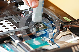 Hand a repairman uses thermal paste syringe apply thermal compound to a CPU. Master replaces thermal grease