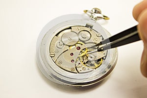 Hand repairs mechanical watch on white background