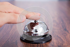 Hand ringing service bell kept on wooden table