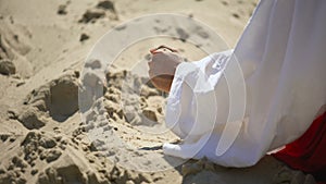 Hand in robe pouring sand, concept of passing life, time is fleeting, back view