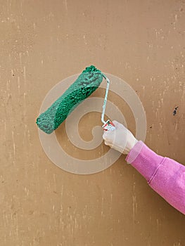 hand with a roller for painting the wall green