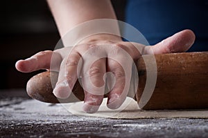 Hand on a rolling pin preparing pizza dough