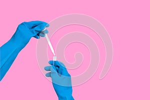 Hand in rubber glove with dropper into test tube in lab on pink background