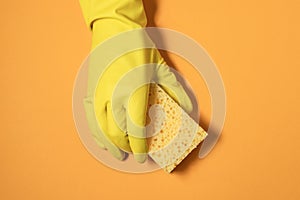 A hand in a rubber glove holds a cleaning sponge. monochrome photography in yellow colors. household chores and cleaning concept