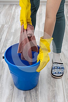 a hand in a rubber glove wets a rag in a bucket of water