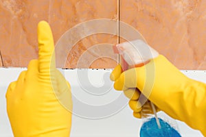 Hand in rubber gloves indicates mold in the bathroom