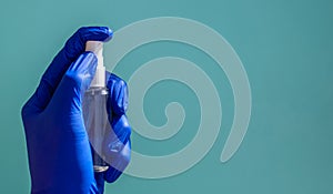 A hand in a rubber medical glove sprays anaesthetic on a green background