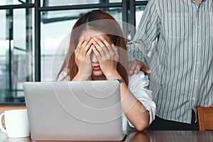 Hand`s of colleague comforting depressed sad Asian woman with hands on face crying on the workplace in office.