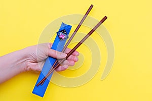 Hand`s holding brown wooden chopsticks i made of bamboo in blue cases