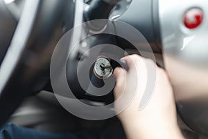 Hand s man plug in a key starting the engine of a car.