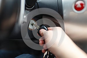 Hand s man plug in a key starting the engine of a car.