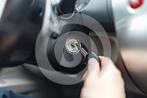 Hand s man plug in a key starting the engine of a car.