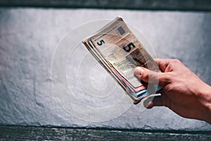 HandÂ´s of young man holding a money. Banknotes on a stone background. Euro money bank notes of different value.