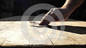 hand sands wooden boards in the suns rays. sanding wood. Processing wood with sandpaper.movement of dust in the suns