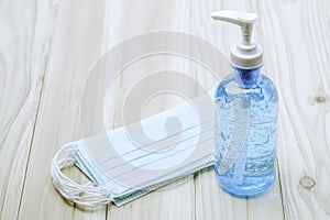 Hand sanitizer bottle or alcohol gel and stacked of surgical face mask on wooden table with cpoy spcae